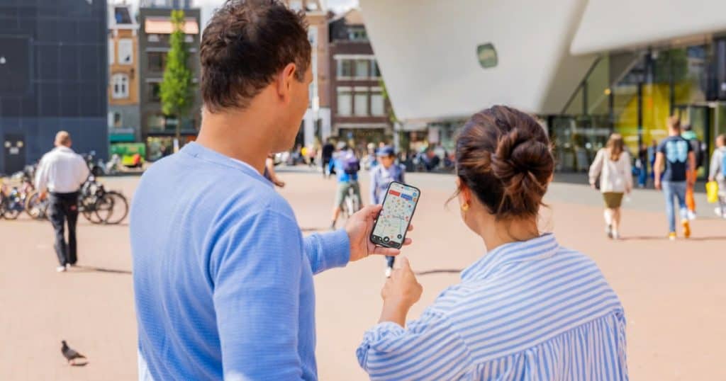 Couple using the I Amsterdam Card App at Museum square in Amsterdam.